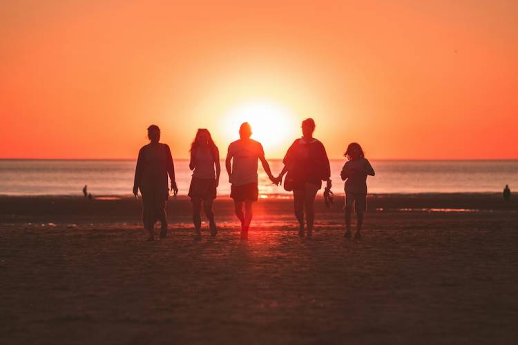 family walking on the beach during sunset